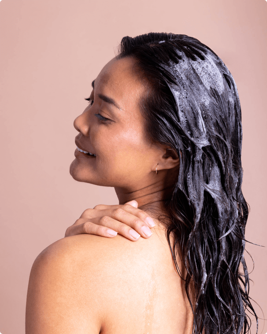 woman rubbing hair care product on her shoulder 